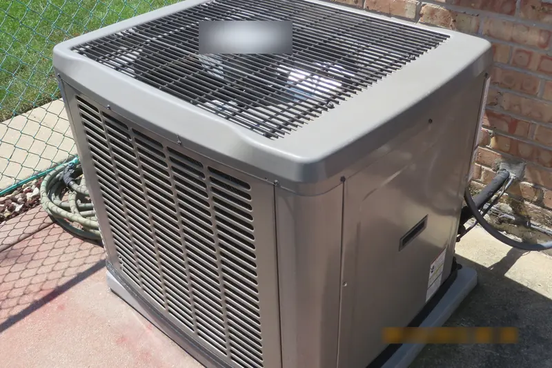 An air-conditioning condenser on its pad by a brick wall, with its refrigerant lines running into the house