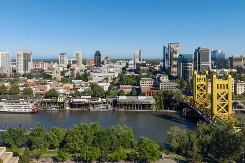 Downtown Sacramento skyline seen across the river on a clear day, with the gold-painted Tower Bridge on the right